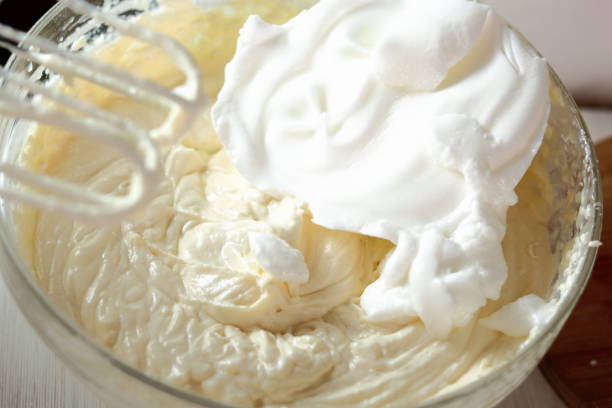 istock Adding whipped egg whites into cheese filling. Making frozen strawberry cheesecake series. 685077990