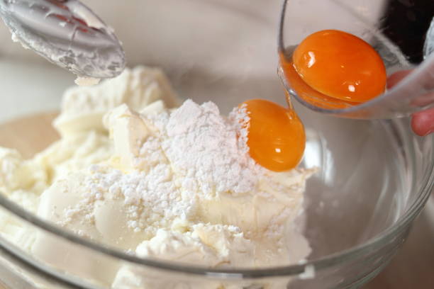 istock Adding egg yolks into cheese filling. Making frozen strawberry cheesecake series. 685091372