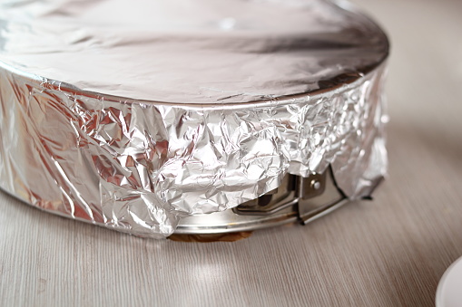 Covering baking pan with foil before and place to fridge. Making frozen strawberry cheesecake series.