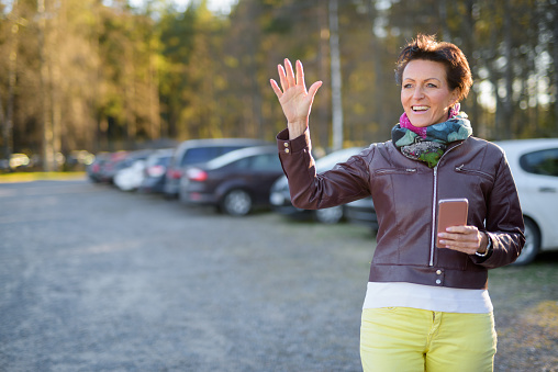 Beautiful woman waving at parking lot horizontal shot