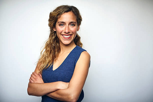 businesswoman with arms crossed over white - bras croisés photos et images de collection