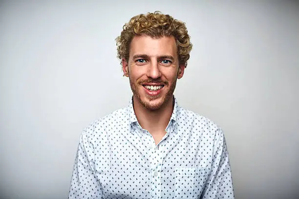 Portrait of male professional with curly hair. Mid adult businessman is smiling. He is over white background.