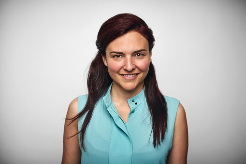 Portrait of mid adult businesswoman smiling. Female executive is wearing smart casual. She is against white background.