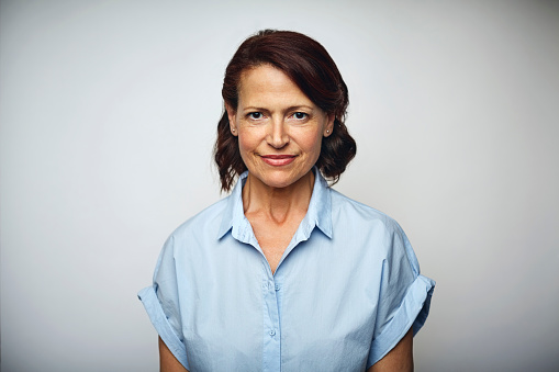 Portrait of confident businesswoman smiling. Female executive is wearing blue shirt. Professional is over white background.