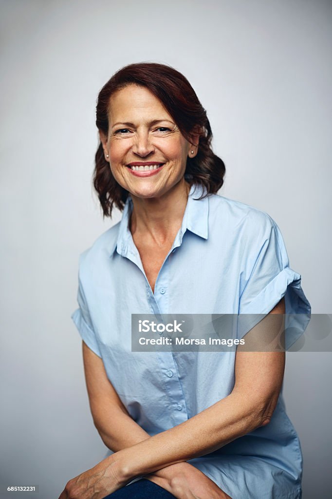 Businesswoman smiling over white background Portrait of businesswoman smiling. Confident executive is wearing blue shirt. Female professional is smiling over white background. Women Stock Photo