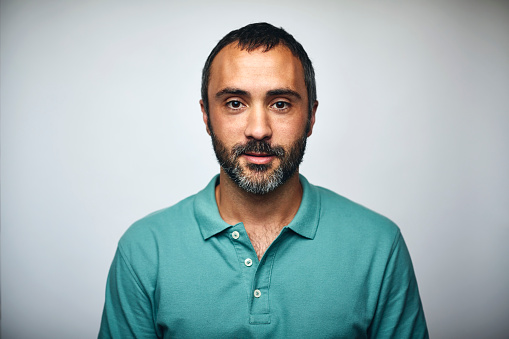 Portrait of mature businessman. Executive is wearing T-shirt. He is against white background.