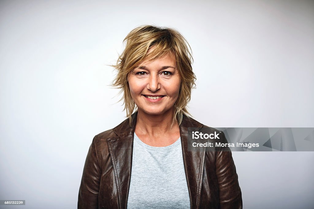 Businesswoman wearing leather jacket over white Portrait of mature businesswoman wearing leather jacket. Female is smiling. She is over white background. Portrait Stock Photo