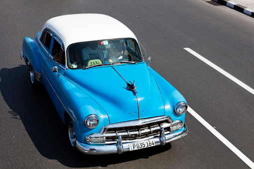 Vintage American car, 1952 Chevrolet Deluxe, used as a taxi, driving down El Malecon in Havana, Cuba, elevated view.