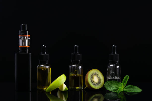 istock Concept of electronic cigarette and fruit flavors on a black background with a hatching 685150584