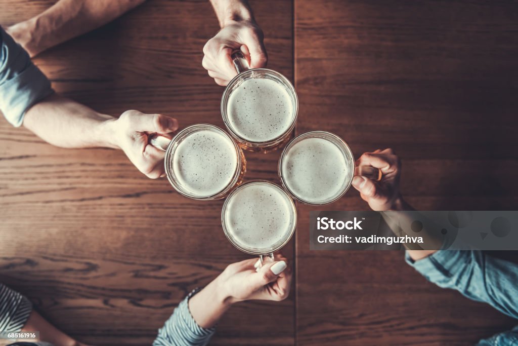 People holds mugs Cheers! Top view of people holding mugs with beer. Beer - Alcohol Stock Photo