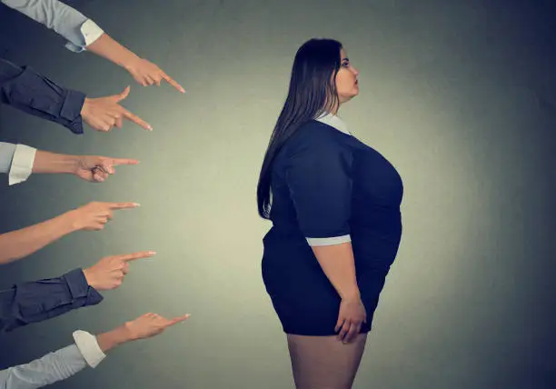 Photo of Many fingers pointing at fat woman