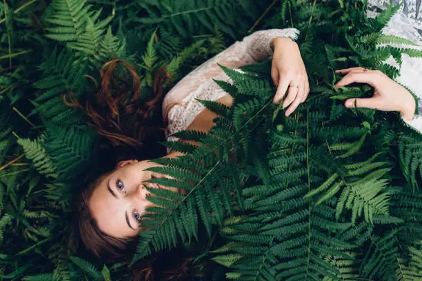 Photo of girl with red hair in an armful of ferns