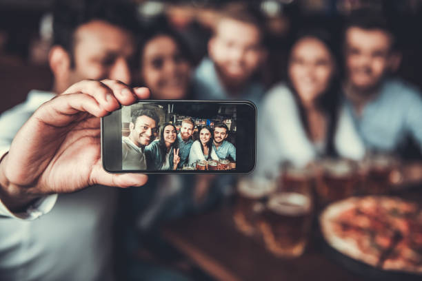 Friends makes selfie Selfie time! Handsome friends making selfie and smiling while resting at pub. celebratory toast photos stock pictures, royalty-free photos & images
