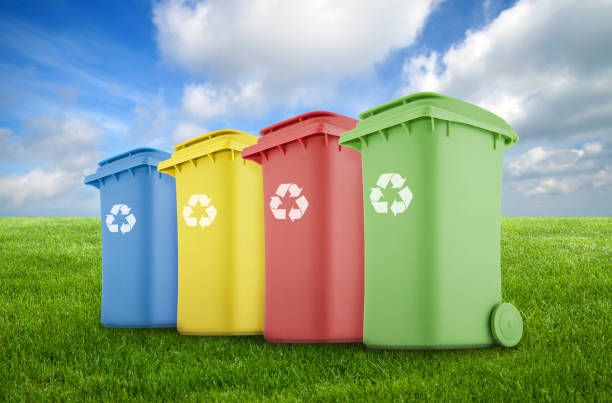 Four colorful recycle bins on green grass.