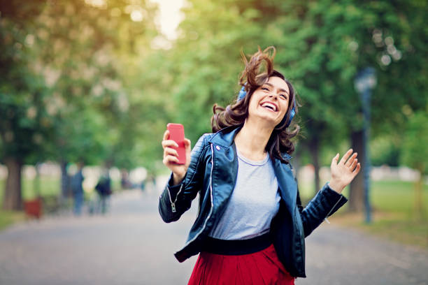 joven está bailando y escuchando la música hasta caminar en el parque - funky people cool women fotografías e imágenes de stock