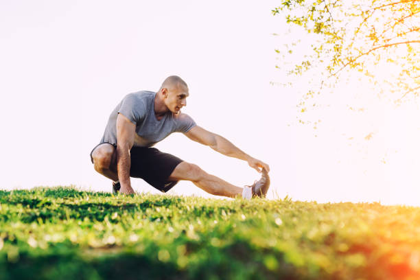 istock young athletic runner doing stretching exercise, preparing for workout in the park. sunset 685214838
