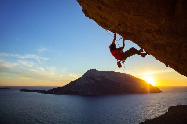 istock Young man climbing overhanging cliff at sunset 685232556