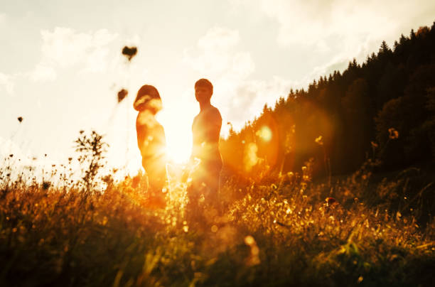 junge in liebe paar bleiben auf wiese in hellem sonnenuntergang licht - teenage couple stock-fotos und bilder