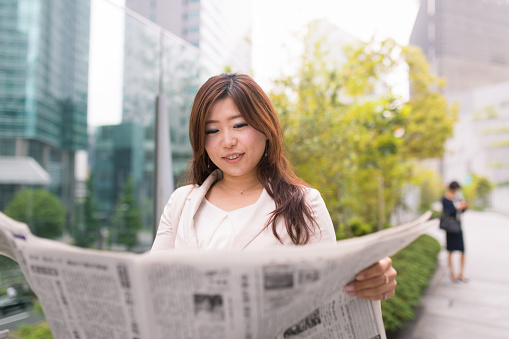 Career woman reading newspaper in city