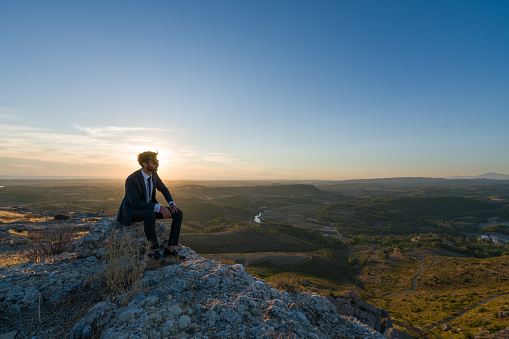 Image of a businessman freedom  on the top of a high mountain sunset.