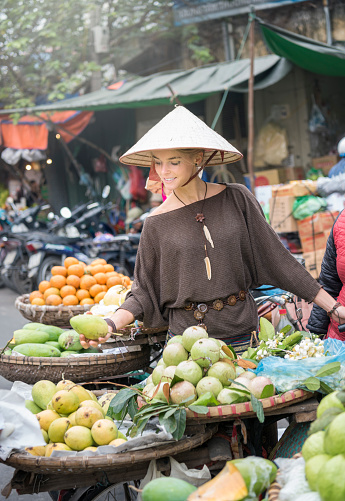 Beautiful female Tourist at the local Fruit Market in Hanoi the Capital of Vietnam. Nikon D810. Converted from RAW.