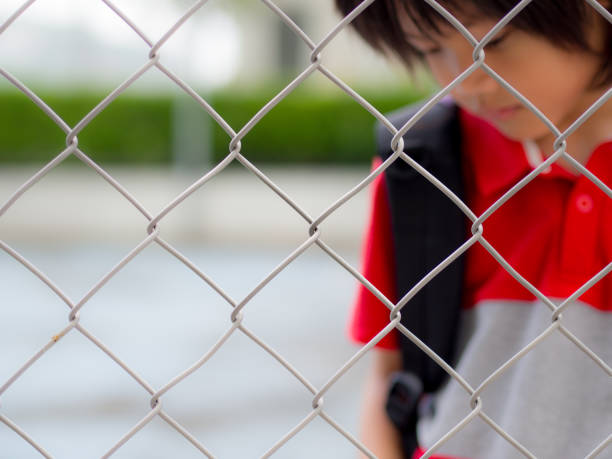 istock Portrait of handsome sad boy behind fence mesh netting. 685371496