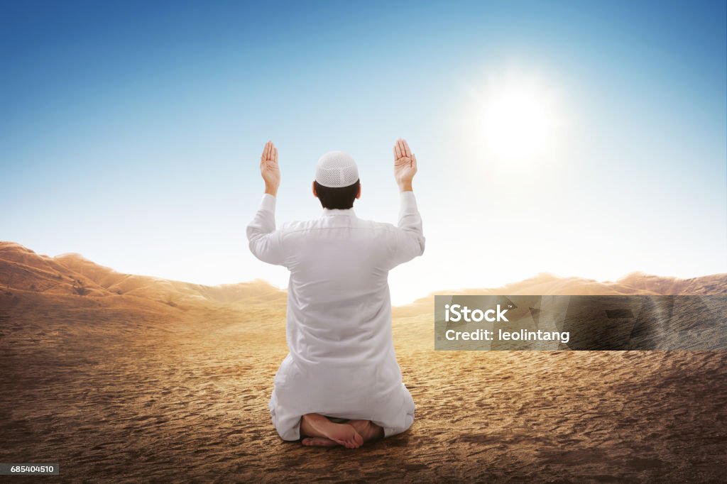 Rear view of asian muslim man sitting and praying Rear view of asian muslim man sitting and praying at desert background Praying Stock Photo