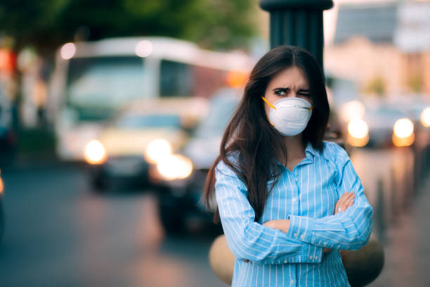 woman with respiratory mask out in polluted city - illness mask pollution car imagens e fotografias de stock