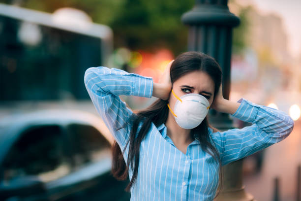 Girl With Mask Covering her Ears Because of Noise Pollution Worried woman fighting urban pollution with safety measures semi truck audio stock pictures, royalty-free photos & images