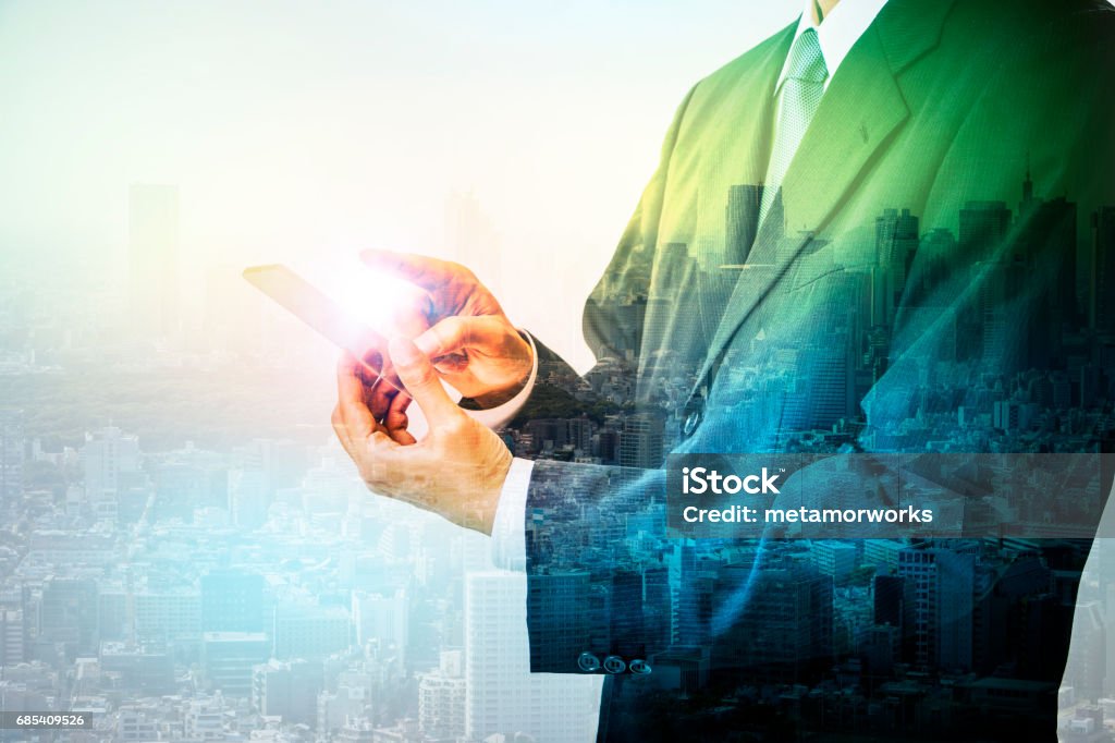 Double exposure of a business person holding smart phone and modern cityscape, conceptual abstract People Stock Photo