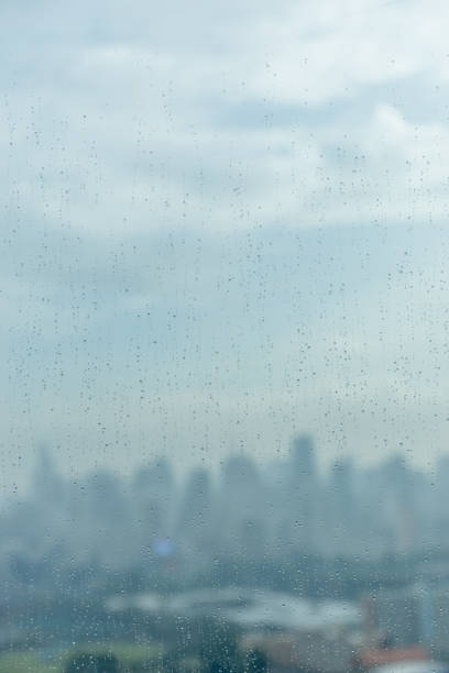 istock Rain drops on window glass and blurred cityscape and sunlight in background. 685409792