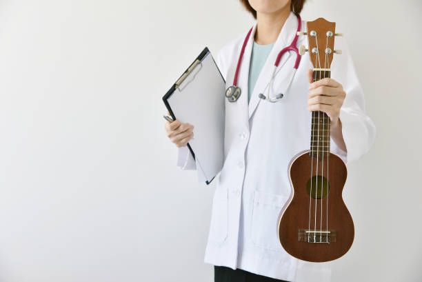 istock Doctor hand holding ukulele (musical instrument), Music therapy concept. 685414356
