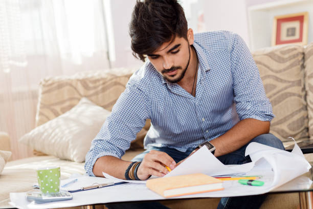 istock Young businessman working at home. He sitting on sofa with laptop and looking at blueprints. 685425190