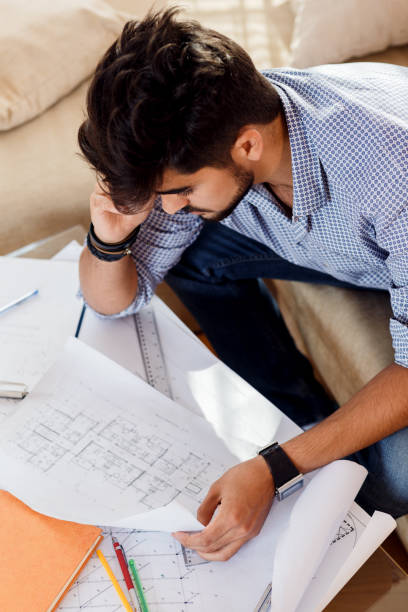 istock Young businessman working at home. He sitting on sofa with laptop and looking at blueprints. 685425326