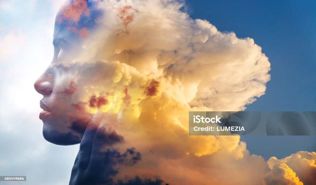 Double exposure, close-up of an African American girl and layers of stunning fluffy clouds The texture of nature combines with the natural beauty of a young attractive female with dark skin Mental Health Stock Photo