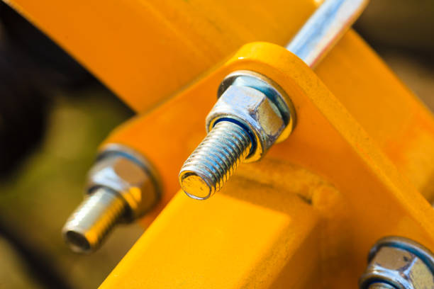 Construction machines concept. Detailed closeup of screw and bolts on yellow indrustrial machinery