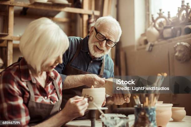 Woman Painting Clay Pot With Senior Potter At Workshop Stock Photo - Download Image Now