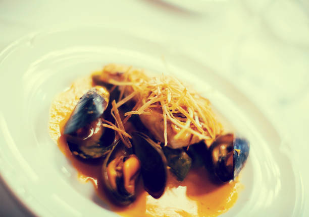 baked white fish with mussels on a plate, close up