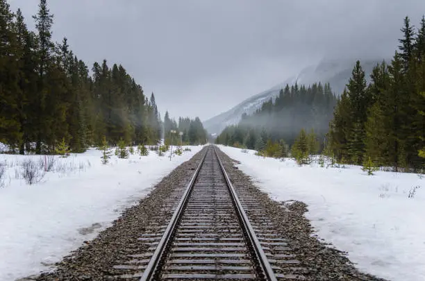 Photo of Straight Railway Track through a Foggy Winter Landscape