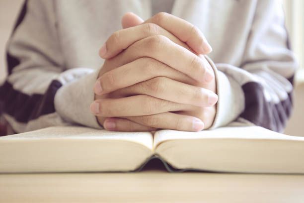 istock Praying on a wooden table with an open Bible 685492430