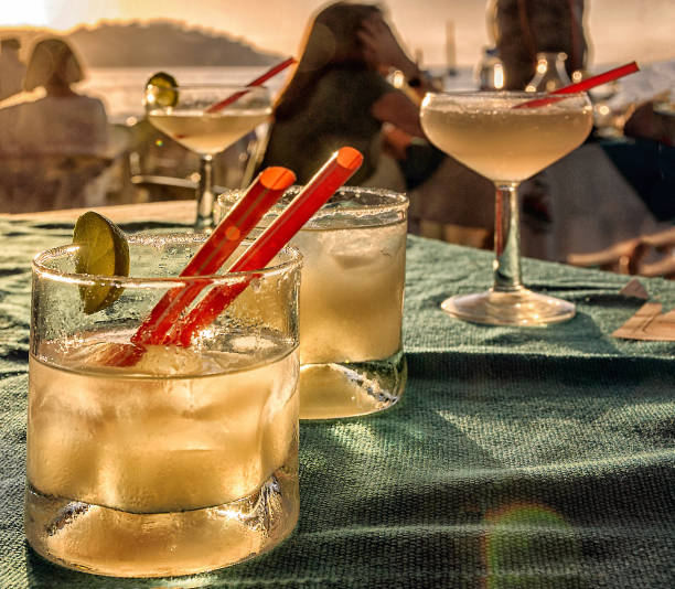 Beach bar table with margarita cocktail drinks and beach sunset background