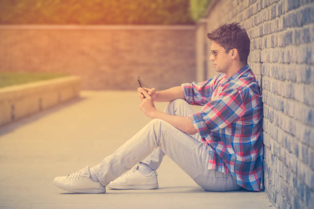 istock Urban man sitting and leaning against the wall and using smartphone 685498344