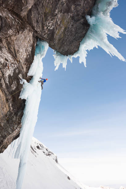 istock Man ice climbing on icicle hanging on steep rock wall 685499496