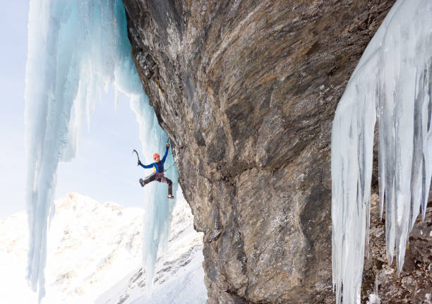 istock Man hanging on ice axe while climbing on frozen rock wall 685499628