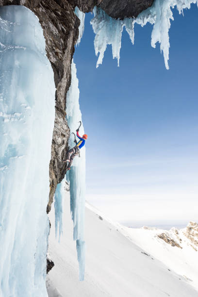 istock Man ice climbing on frozen steep wall using ice axes 685499692