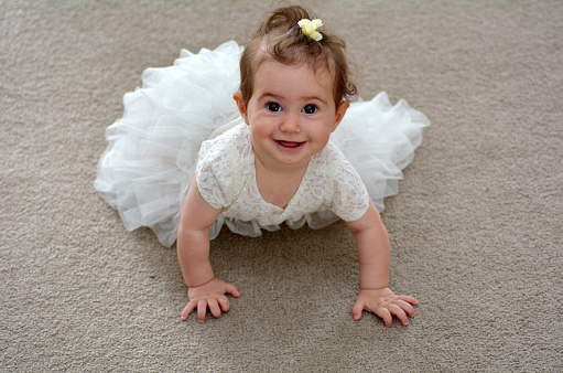 Happy baby flower girl crawl on the ground on wedding day.
