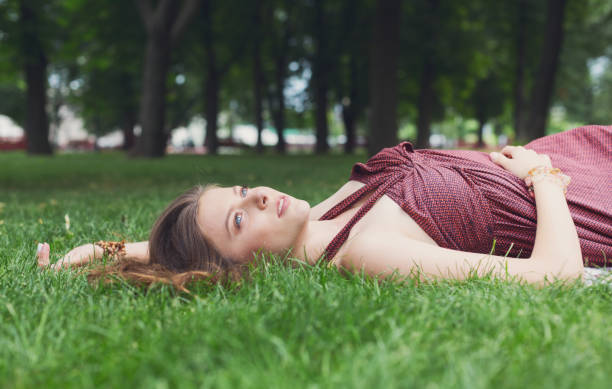istock Beautiful young girl lying on grass in summer park 685526712