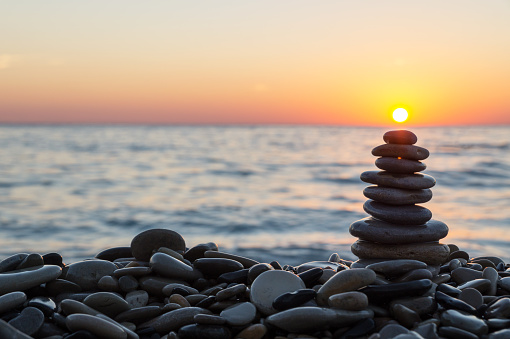 Cairn stones stacked with sun on the stony beach on sundown.