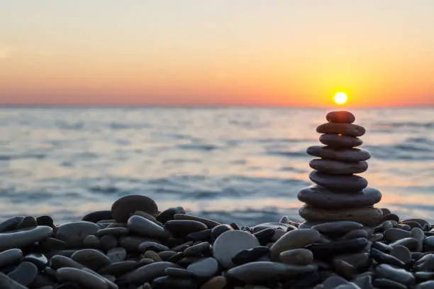 Photo of Cairn stones with sun on the beach on sundown