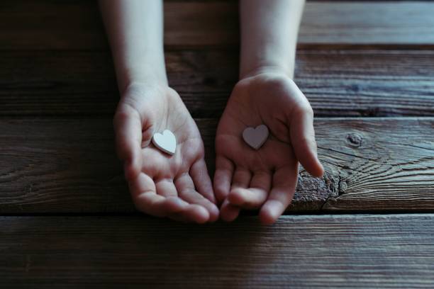 enfant tenant des coeurs blancs en mains sur une table en bois. - praying charity and relief work fundraiser heart shape photos et images de collection